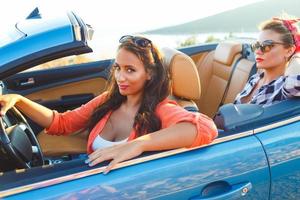 Two young happy girls driving a cabriolet photo