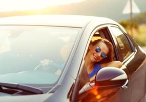 Smiling woman driving a car at sunset photo