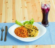 Dish made of two kinds of rice on a white plate and a glass of juice with ice photo