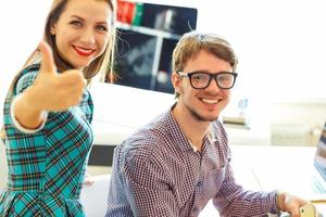 Beautiful young woman and man with thumb up in office photo