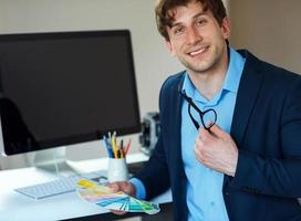 Man looking to a color paint palette at home office photo