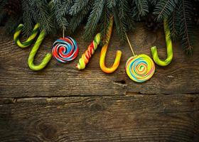 Navidad frontera con abeto árbol sucursales, pino conos y caramelo caña en rústico de madera tableros foto