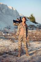 joven hembra soldado vestido en un camuflaje con un pistola en el ubicación foto