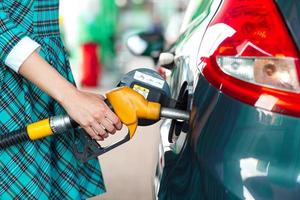 mujer llena gasolina dentro el coche a un gas estación foto