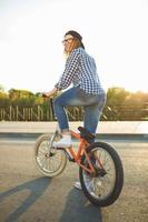 Lovely young woman in a hat riding a bicycle on city background in the sunlight outdoor