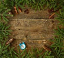 Christmas tree branch with cones, cinnamon, dittany and blue alarm on wooden background with copyspace photo