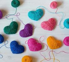 Multicolored Hearts with a balls of thread on white wooden background photo