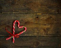 Candy canes in the heart shape on a wooden background photo