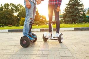 A young couple riding hoverboard - electrical scooter, personal eco transport, gyro scooter, smart balance wheel photo