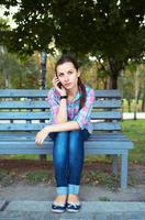 Portrait of a young woman in a park talking on the phone photo