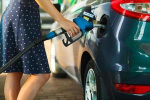 mujer llena gasolina dentro el coche a un gas estación foto