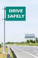 Message DRIVE SAFELY on green road sign with highway road view photo