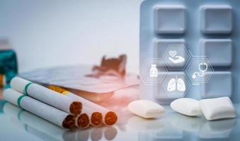 Quit smoking or smoking cessation with nicotine replacement therapy or NRT. 31 May World No Tobacco Day. Nicotine chewing gum in blister pack near pile of cigarettes. Nicotine products to stop smoke. photo