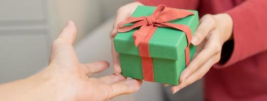 Navidad víspera festival temporada día, manos de joven mujer, niña participación regalo envase verde caja con rojo cinta, arco. contento a obtener recibido presente en alegre Navidad. celebracion en nuevo año festival personas