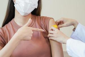 Covid-19,coronavirus hand of young woman nurse,doctor giving syringe vaccine, inject shot to asian arm's patient. Vaccination, immunization or disease prevention against flu or virus pandemic concept. photo