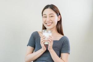 Happy, asian young woman, girl drinking a glass of white fresh, warm or hot dairy milk for calcium, vitamin wholesome good nutrition in morning. lifestyle, product healthy people, Isolated background. photo