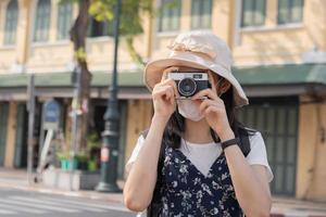 Traveler, travel asian young woman or girl use camera take photo, old town street, city tourism on happy sunny day. Backpacker tourist, holiday trip, summer or vacation, hobby concept. photo
