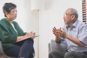 Psychology, depression people. Elderly asian adult man, men consulting with psychologist ,psychiatrist while elderly, old patient counseling mental with doctor woman at clinic. Encouraging, therapy. photo