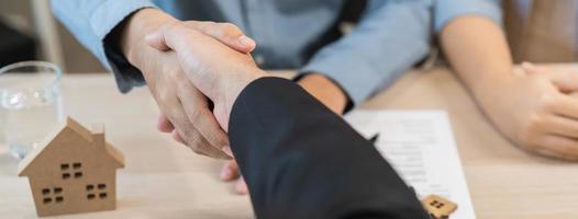 Close up hand of young couple new landlord, tenant or rental handshake with home, apartment agent or realtor woman after bank approved mortgage, loan signed purchase contract. Property of financial. photo