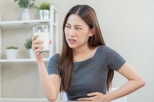 Pain, Allergy asian young woman, girl hand in belly suffer after drink glass of milk, unhappy and bad stomach ache. Lactose intolerance and dairy food , health problem concept. photo