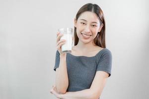 Happy, asian young woman, girl drinking a glass of white fresh, warm or hot dairy milk for calcium, vitamin wholesome good nutrition in morning. lifestyle, product healthy people, Isolated background.