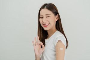 retrato de bonito, hermosa asiático joven, Adolescente atractivo después conseguir, recibir anti virus vacuna COVID-19. demostración brazo en blanco vendaje aislado en blanco fondo, Copiar espacio. foto