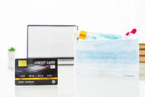 Credit card front of laptop screen with hand sanitizer and surgical mask photo