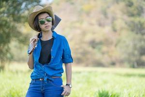 mujer usa sombrero y lleva su guitarra en el campo de hierba foto