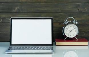 Laptop mockup and alarm clock with wood background on the work table photo