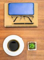 Top view image of coffee cup and cellphone on wooden table photo