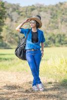 mujer usa sombrero caminando y lleva su bolso de guitarra foto