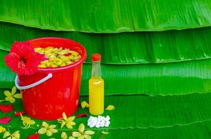 Songkran festival background with flowers in water bucket, scented water and marly limestone on wet banana leaf background. photo