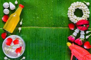 Tailandia Songkran festival antecedentes con agua pistola, guirnalda, perfumado agua y flor en plata cuenco poner en mojado plátano hoja. foto