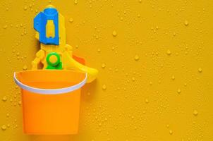 Water gun in bucket on wet yellow background for Thailand Songkran festival concept. photo