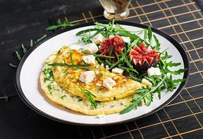 tortilla con queso feta queso, perejil y ensalada con higos, Rúcula en blanco lámina. frittata - italiano tortilla. foto