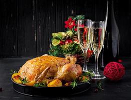 Baked turkey or chicken. The Christmas table is served with a turkey, decorated with bright tinsel. Fried chicken, table setting. Christmas dinner. photo