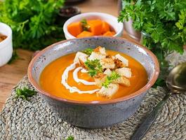 Pumpkin soup in a bowl served with parsley and croutons. Vegan soup. Thanksgiving day food. Halloween meal. photo