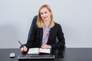 Beautiful businesswoman working on a laptop. Female freelancer connecting to internet via computer. Blogger or journalist writing new article. photo