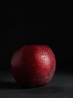 cerca arriba de rojo jugoso manzana con gotas de agua en un negro antecedentes. aislar. Copiar espacio foto