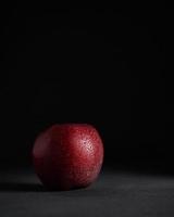 Red juicy Apple with drops of water on a Black Background. Vertical shot. Isolate. Copy space photo