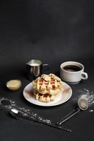 Homemade of Breakfast tasty Waffles, Caramel Sauce, Coffee Cup, Milk, dessertspoon, strainer on a Black concrete Background photo