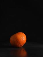 Juicy ripe Mandarin on a Black Background. Vertical shot. Isolate. Copy space photo