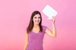 Woman showing sign speech bubble banner looking happy excited on pink background. Beautiful young joyful model on pink background having idea. photo