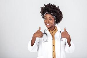 Happy african female doctor wear white lab coat, stethoscope look at camera and showing thumbs up. Smiling afro american woman professional therapist physician portrait. photo