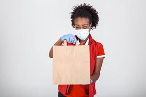 Delivery woman holding paper bag in medical rubber gloves and mask . copy space. Fast and free Delivery transport . Online shopping and Express delivery . Quarantine photo