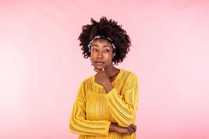 Suspicious annoyed young african american woman with distrustful face looking at camera, skeptical sarcastic black girl feeling cautious dubious distrusting isolated on pink studio background photo