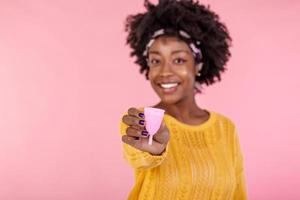 Serious dark skinned woman holds bell shaped menstruation cup for inserting in vagina, trapping menstrual fluid and leakage protection, tells secret information and tips how to use it, makes hush sign photo