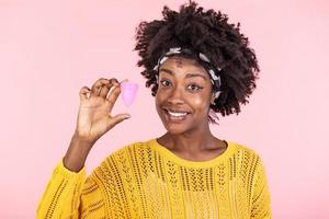 Portrait of woman holding menstrual cup isolated over pink studio background, happy female having period, dislike to use napkins or pampons. Women health concept, zero waste alternatives photo