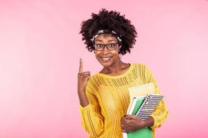 Young female student in glasses holding books in hand isolated on pink background portrait, casual daily lifestyle student holding notebooks smiling