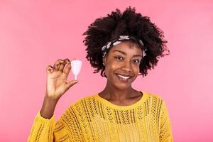 Portrait of woman holding menstrual cup isolated over pink studio background, happy female having period, dislike to use napkins or tampons. Women health concept, zero waste alternatives photo